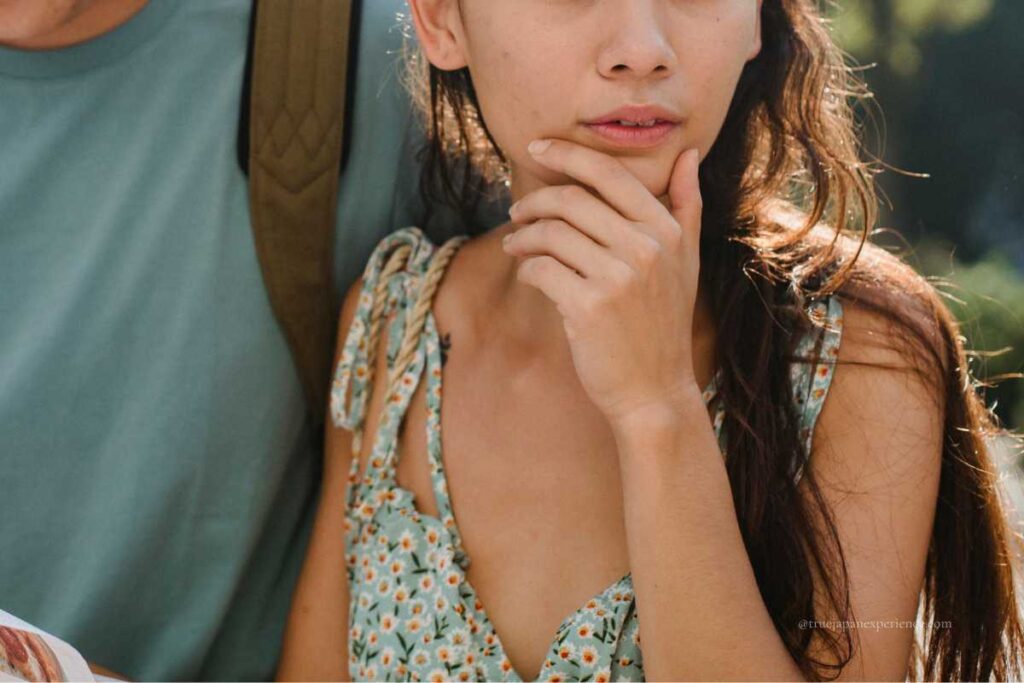 A woman in a floral dress touching her chin with a thoughtful or worried look