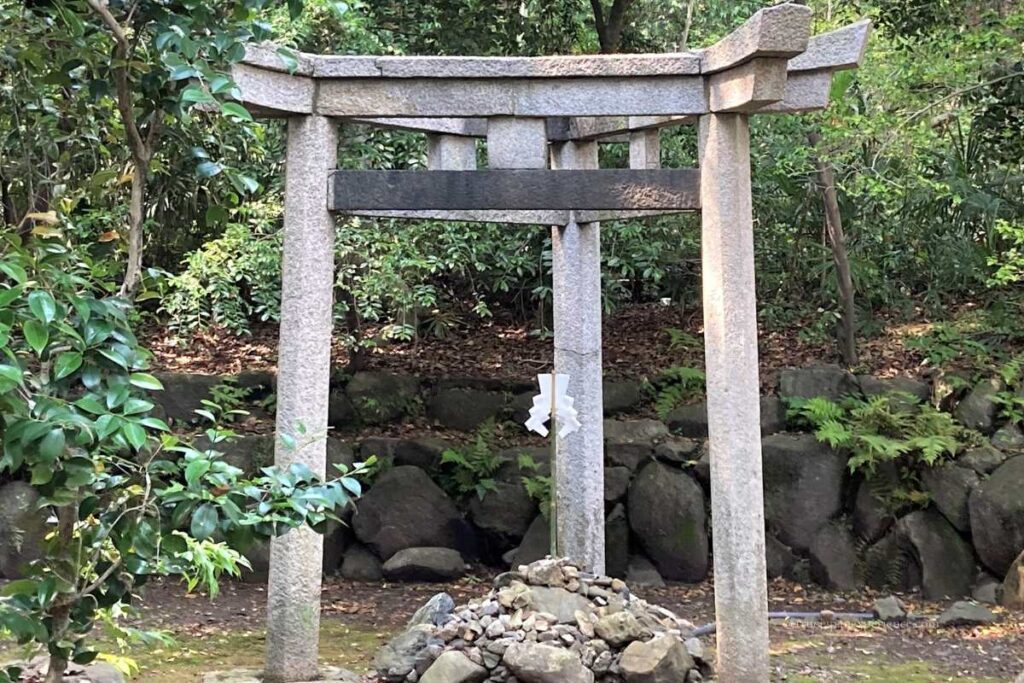 A rare stone Miwa Torii with three pillars standing in the sacred grounds of Kaiko no Yashiro Shrine in Kyoto.