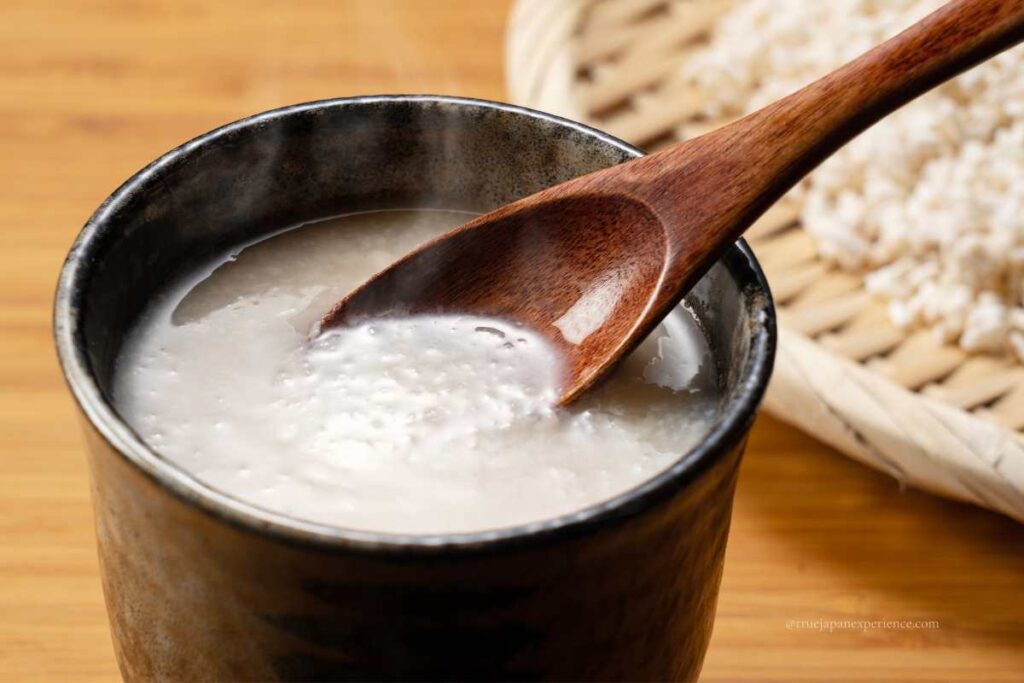 A warm cup of Japanese amazake, a traditional sweet rice drink, with a wooden spoon